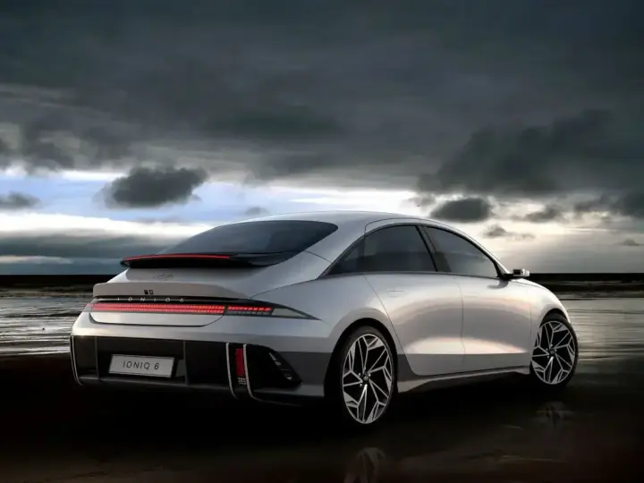 Srebrny Hyundai Ioniq 6 na plaży pod pochmurnym niebem.