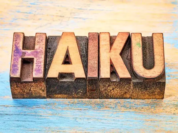 Träbokstäver bildar ordet "HAIKU" på en sliten träyta. En hyllning till den korta, poetiska formen.