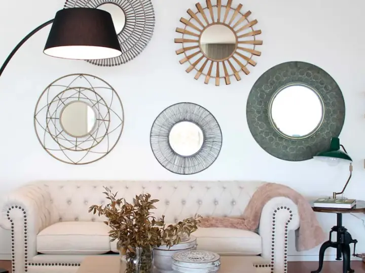 Salón moderno con sofá blanco, lámpara de pie y varios espejos decorativos que siguen principios de feng shui para atraer energía positiva.