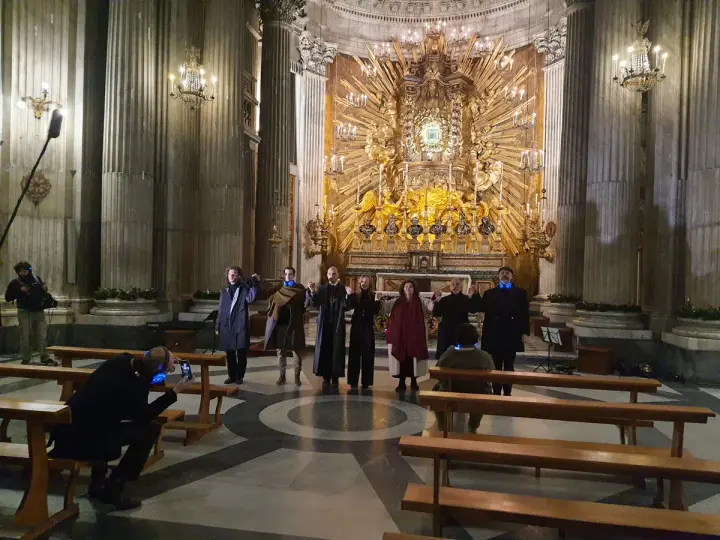 A group of people in a church, some holding hands, with a large golden altar in the background.