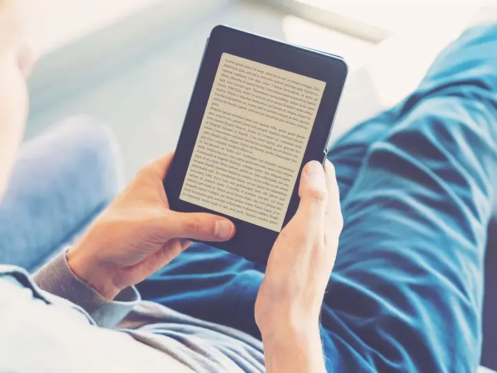 Osoba czyta książki na czytniku e-booków. Wygodny audiobook książki w cyfrowej formie.