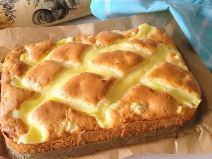 Puszyste ciasto jogurtowe z kremowym nadzieniem, upieczone na papierze do pieczenia.