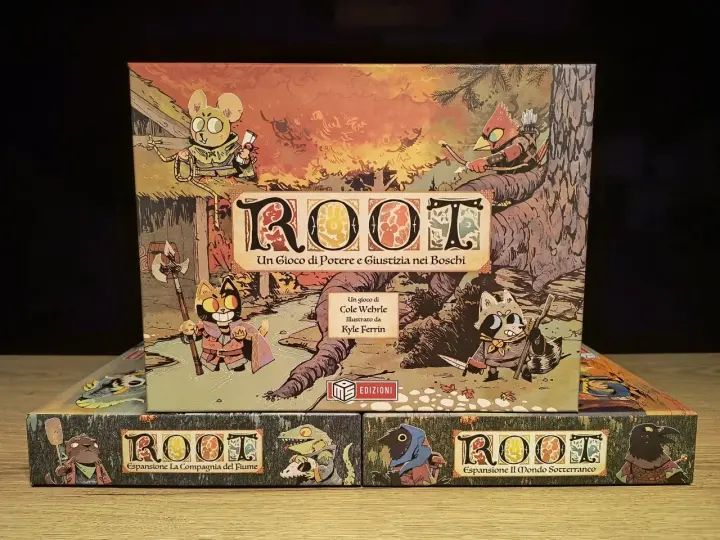 Scatole del gioco da tavolo Root e sue espansioni: La Compagnia del Fiume e Il Mondo Sotterraneo. Personaggi antropomorfi in stile fantasy.
