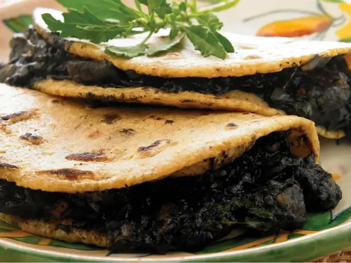 Dos tortillas de maíz rellenas de quelites, un platillo que evoca lo que comían los aztecas.