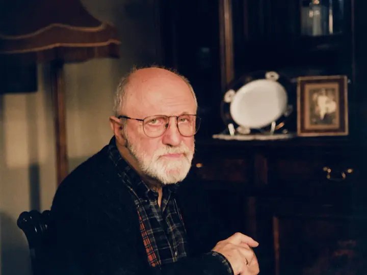 Portret starszego mężczyzny z siwą brodą i okularami. W tle widać meble i ozdobną zastawę. Wiele osób zastanawia się, jak zmarł Henryk Machalica.