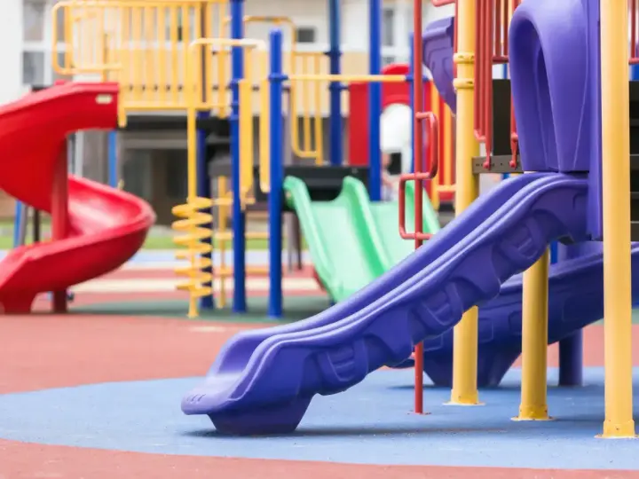 Aire de jeux colorée avec toboggans rouge, vert et violet.
