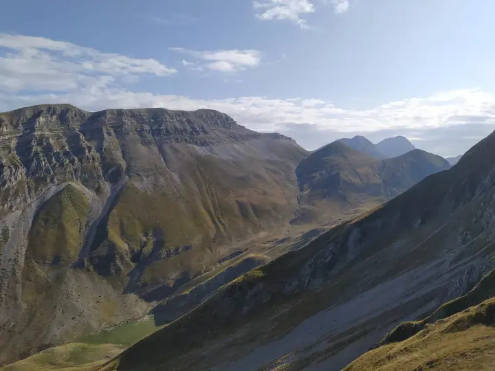 Vaste montagne del Monte Corvo sotto un cielo azzurro con nuvole bianche.