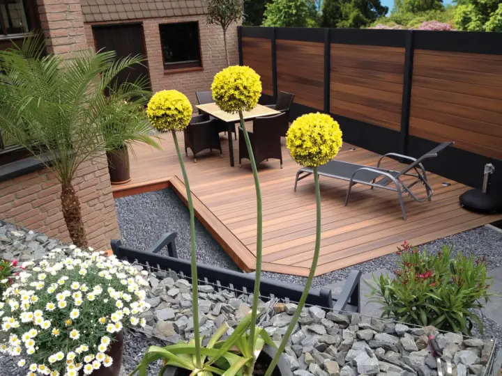 Giardino moderno senza erba: deck in legno, ghiaia, piante in vaso e fiori bianchi. Esempi idee giardino senza erba.
