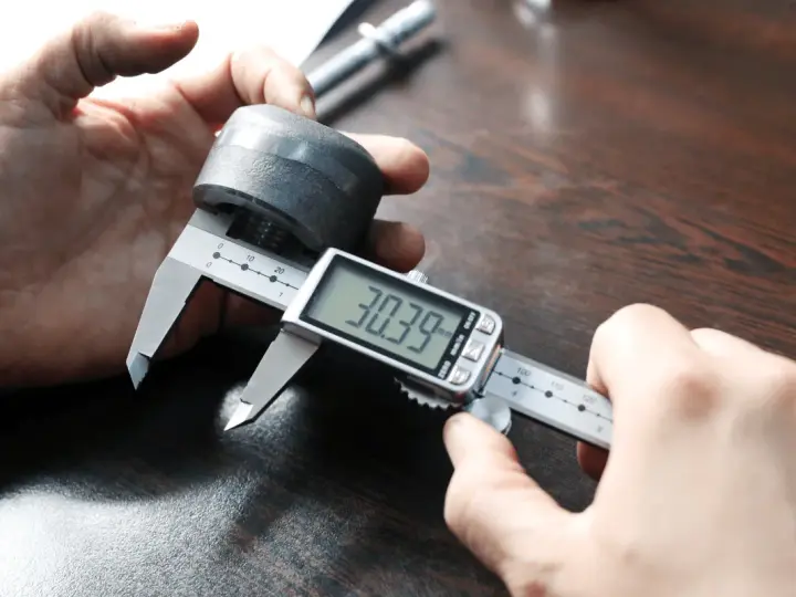 Precyzyjne pomiary: jak mierzyć suwmiarką cyfrową element metalowy, odczyt 30.39 mm.