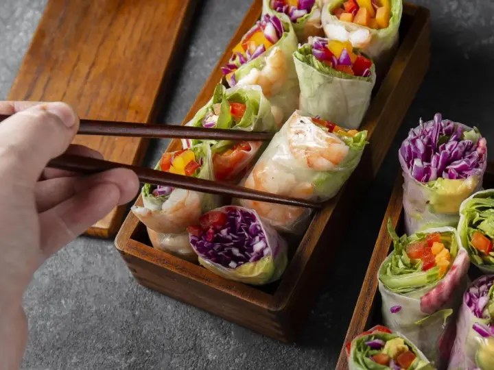 Chwytam pałeczkami świeże sajgonki z krewetkami, czerwoną kapustą i warzywami. Idealne co do sushi!