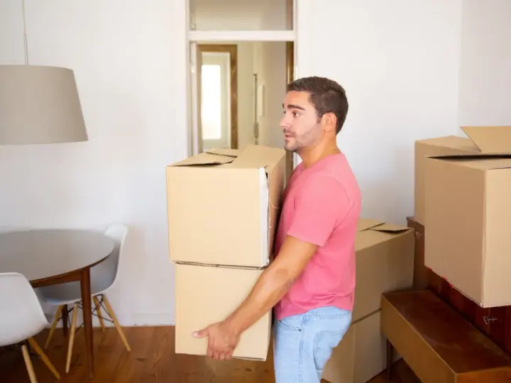 Un homme porte des cartons, prêt à quitter le domicile conjugal. Le propriétaire semble pensif, entouré de cartons de déménagement.