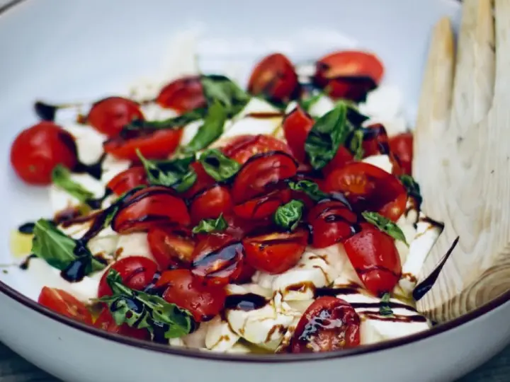 Frische Insalata Caprese mit saftigen Tomaten, cremigem Mozzarella und Basilikum, beträufelt mit Balsamico.