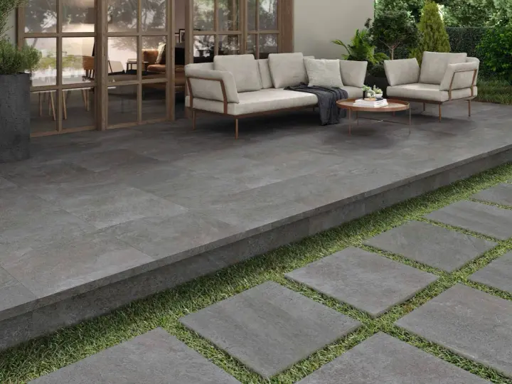 Terraza moderna con suelo de baldosas grises, ideal para saber como poner baldosas en suelo de tierra. Sofá y sillones invitan al descanso.