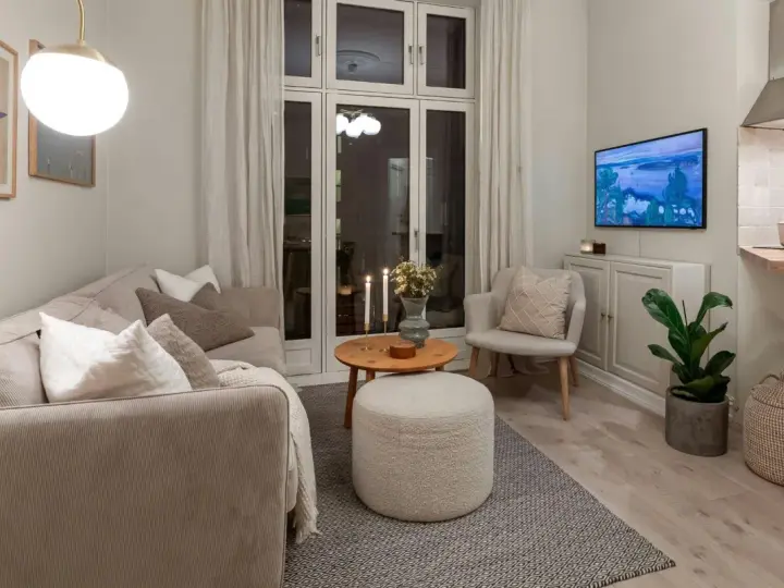 Salon cosy avec canapé, fauteuil, table basse et pouf. Une astuce rangement petit appartement : le meuble bas sous la TV optimise l'espace.