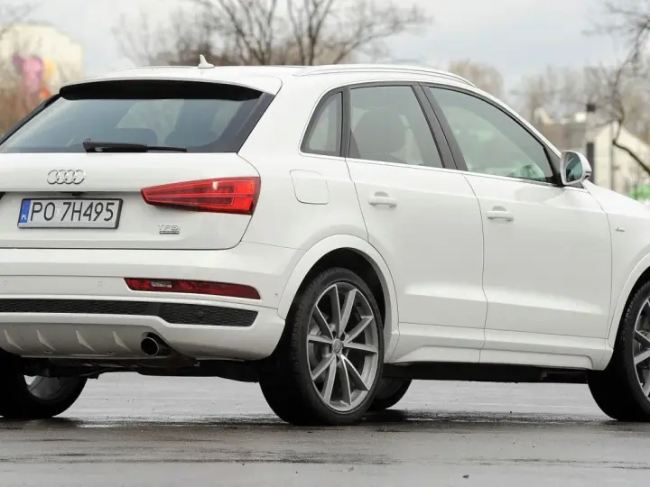 Biały SUV Audi Q3, idealny suv do 70 tys. zł, z polskimi tablicami rejestracyjnymi PO 7H495, widoczny z tyłu i z boku.
