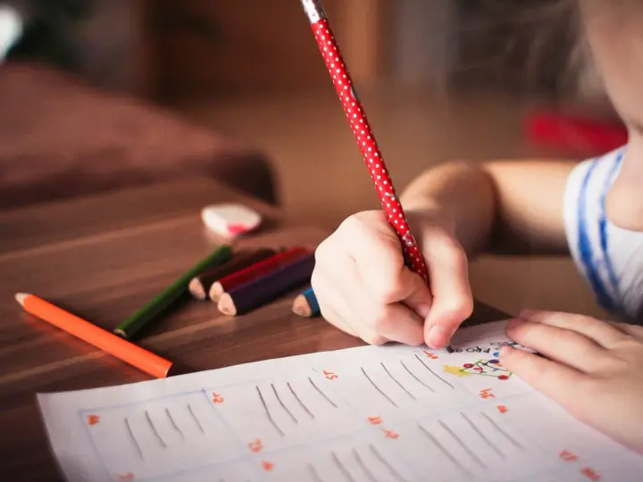 Dziecko zmagające się z dysleksją, dysgrafią, dysortografią i dyskalkulią pisze kredkami.
