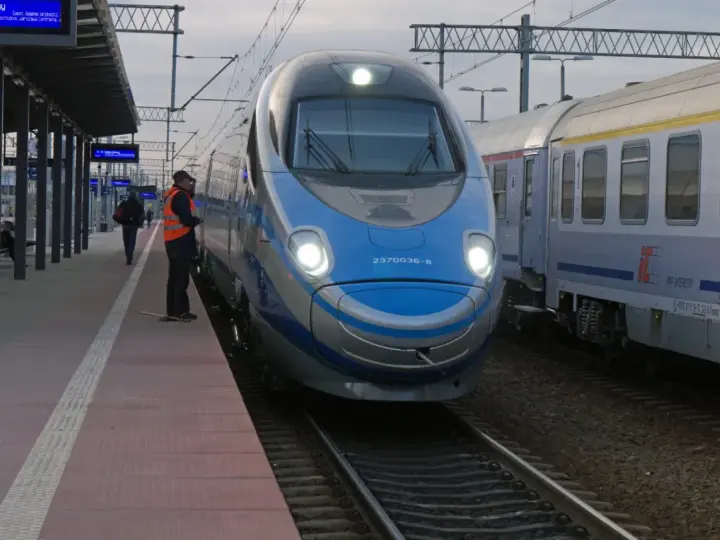 Pendolino Warszawa-Kraków na peronie. Maszynista w kamizelce odblaskowej czeka na pasażerów.