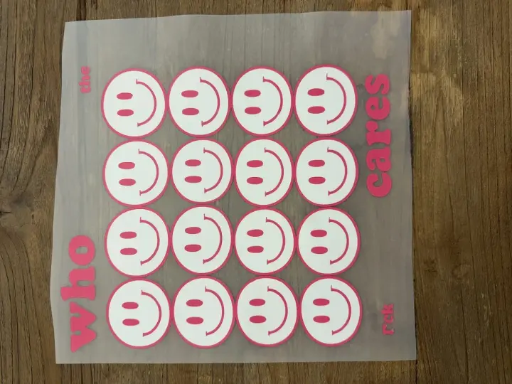Aufkleber mit Smiley-Gesichtern, bereit für das Textildruck-Verfahren. "Who the cares rck" steht auf dem Transferpapier.