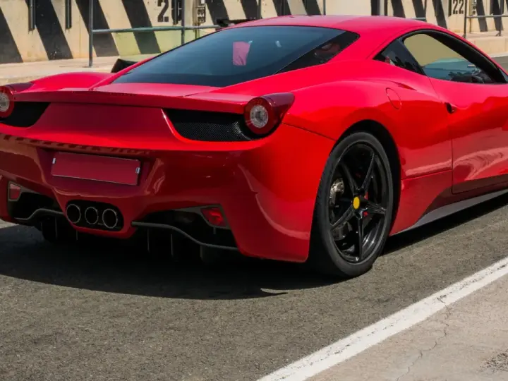 Czerwone Ferrari 458 Italia na torze wyścigowym, widok z tyłu.