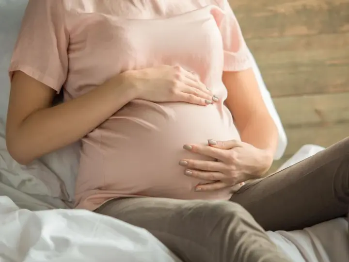 Kobieta w ciąży z dłońmi na brzuchu, martwiąca się o niskie erytrocyty w ciąży.