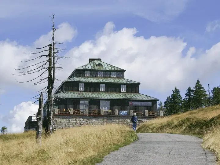 Schronisko Odrodzenie w Karkonoszach, z charakterystyczną architekturą i otoczone suchymi drzewami.