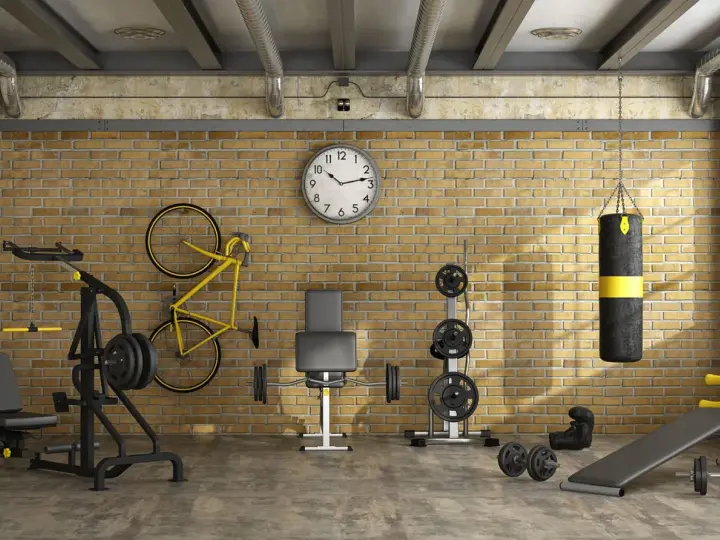 Ett välutrustat gym i garaget med vikter, boxningssäck, cykel och träningsbänk.
