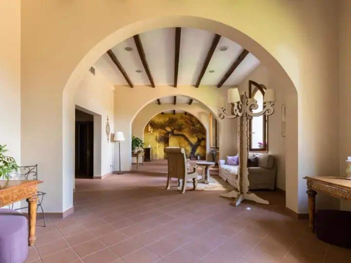 Interno accogliente con archi in pietra, un murale di un albero antico e arredi che evocano l'atmosfera dell'antico borgo di Sutri.