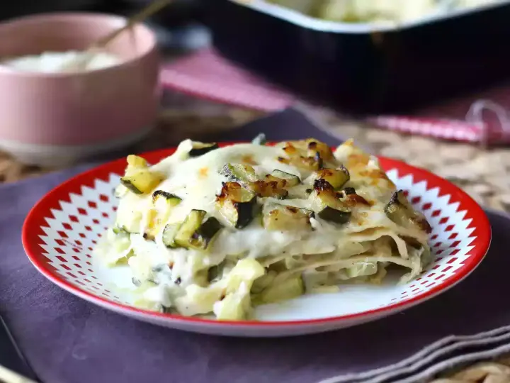 En bit krämig vegetarisk lasagne med zucchini, toppad med gyllene ost och grönsaker.