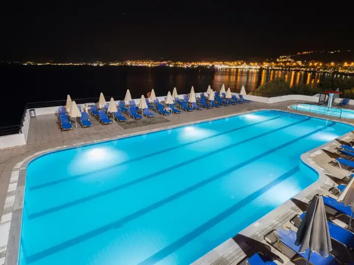 Basen hotelowy nocą, z widokiem na oświetlone miasto na horyzoncie. Idealne miejsce na relaks, jak sugerują pozytywne opinie o horizon beach.