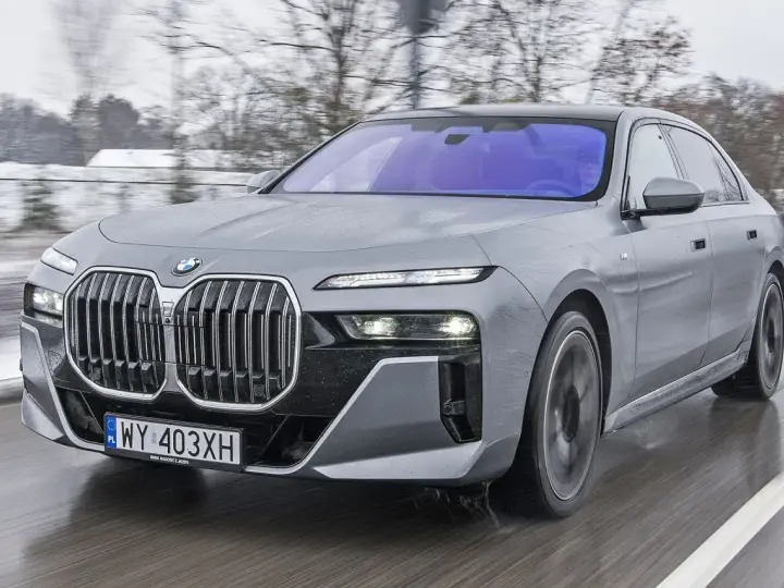 Szary BMW Serii 7 w ruchu, z widocznym grillem i reflektorami. Sprawdź aktualną bmw 7 cena.