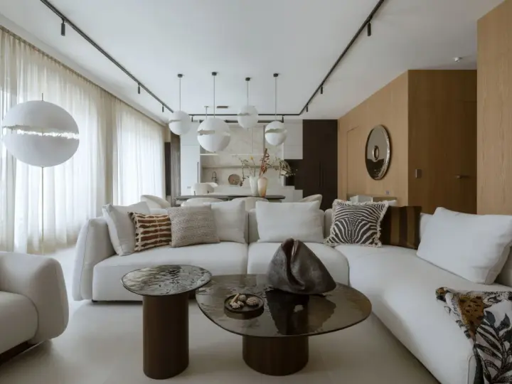 Nowoczesny projekt mieszkania z białą sofą, okrągłymi stolikami i designerskimi lampami.