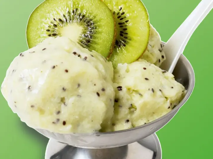 Erfrischendes Kiwi-Eis in einer Schale, garniert mit frischen Kiwischeiben. Ein Löffel steckt darin, bereit zum Genuss.