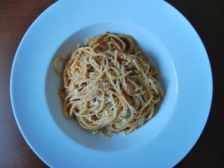 Spaghetti Napoli z sosem pomidorowym i parmezanem, podane w białej głębokiej misce.