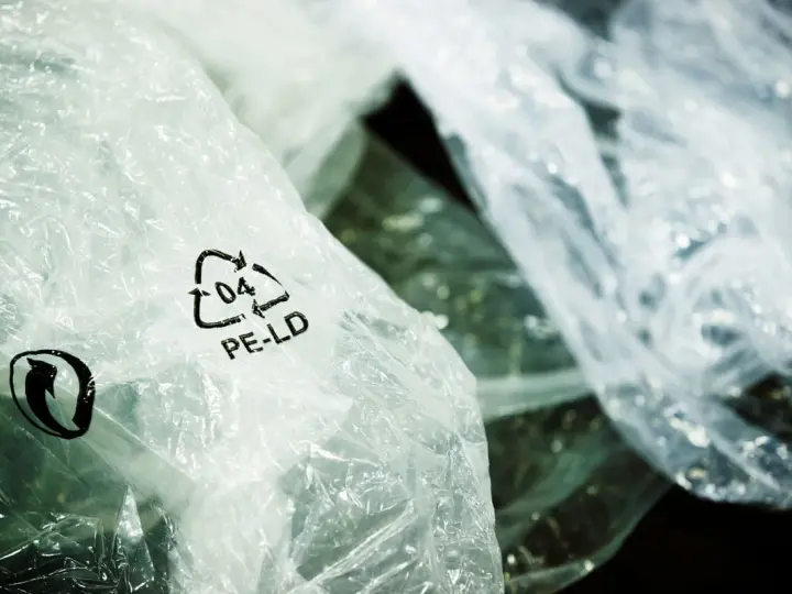 Zgniecione folie PE-LD z symbolem recyklingu. Firma stawia na recykling tworzyw sztucznych, dbając o środowisko.