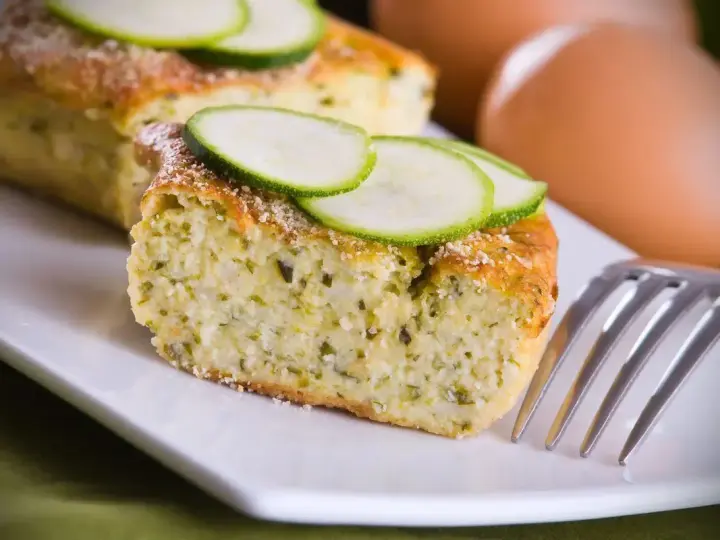 Delizioso sformato di zucchine, soffice e profumato, guarnito con fette di zucchina fresca. Perfetto per un pasto leggero.
