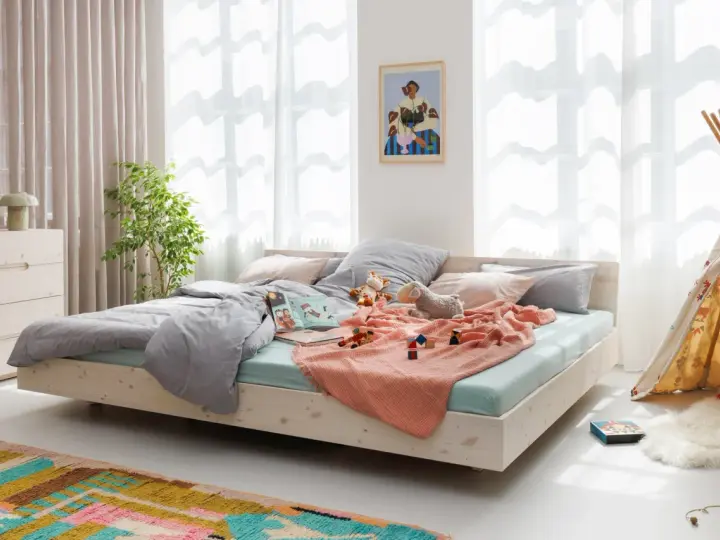 Ein gemütliches Familienbett mit Spielzeug und Kuscheltieren, das zum Kuscheln einlädt. Hier ist Platz für die ganze Familie.