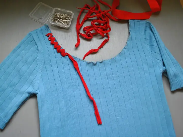Jersey azul de punto con cuello cortado y tijeras.