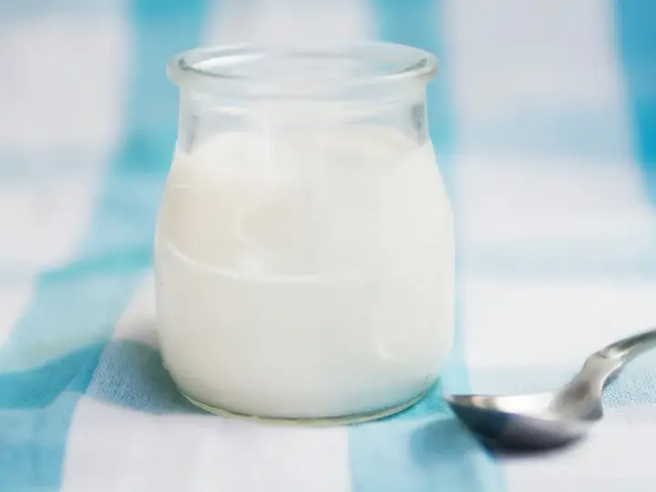 Słoiczek z domowym jogurtem, pełnym naturalnych probiotyków, czeka na łyżeczkę.
