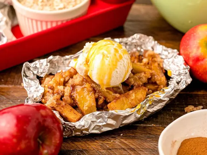 Warm campfire apples, baked in foil, topped with a scoop of vanilla ice cream and drizzled with caramel.