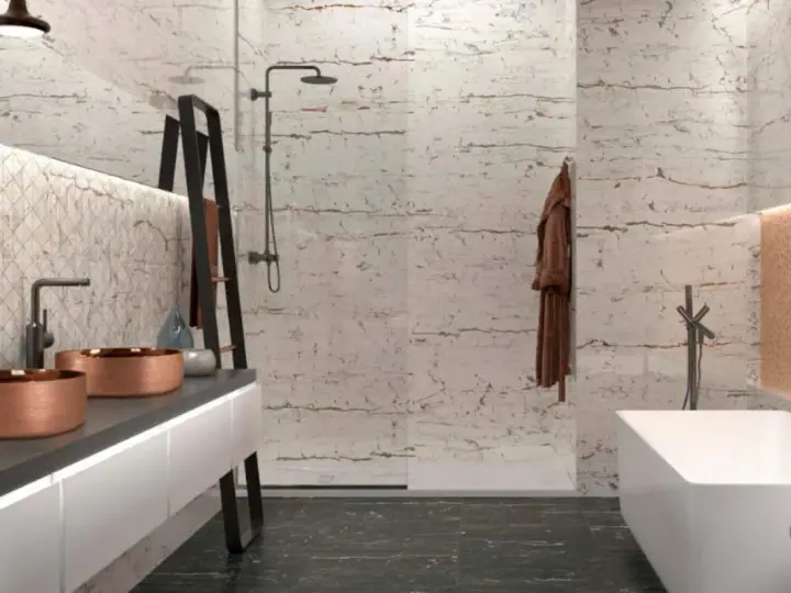Salle de bain moderne avec murs texturés rappelant la pierre de Bourgogne, double vasque en cuivre, baignoire îlot et douche à l'italienne.