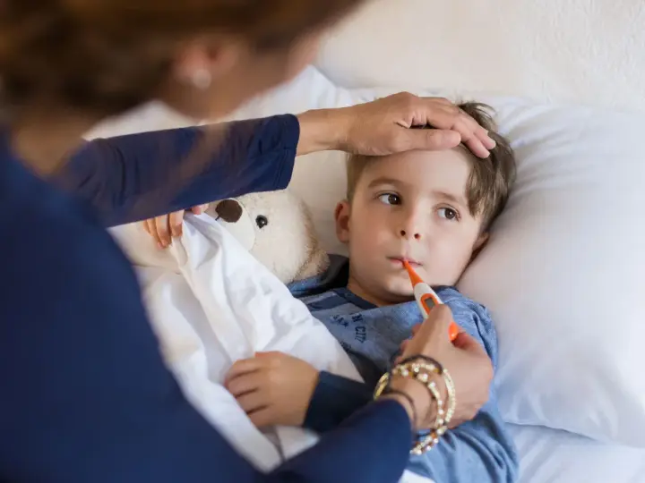 Chłopiec leży w łóżku, mama mierzy mu temperaturę. Znowu choruje, to już drugi raz w tym miesiącu.