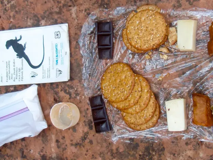 Backpacking lunch ideas no cooking: crackers, cheese, chocolate, dried peas, and jerky laid out on a map.