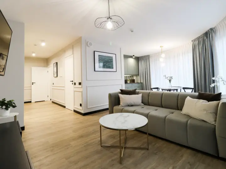 Nowoczesny apartament suite, z wygodną kanapą, stolikiem kawowym i widokiem na kuchnię.