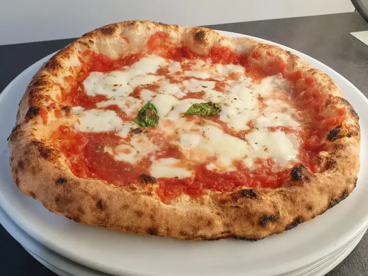 Pizza a lunga lievitazione con pomodoro, mozzarella filante e basilico fresco. Croccante fuori, soffice dentro, un vero capolavoro.