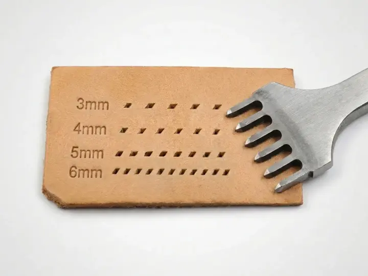 Un punzón de cuero con dientes metálicos crea filas de agujeros en una tira de cuero, mostrando diferentes tamaños de puntadas.