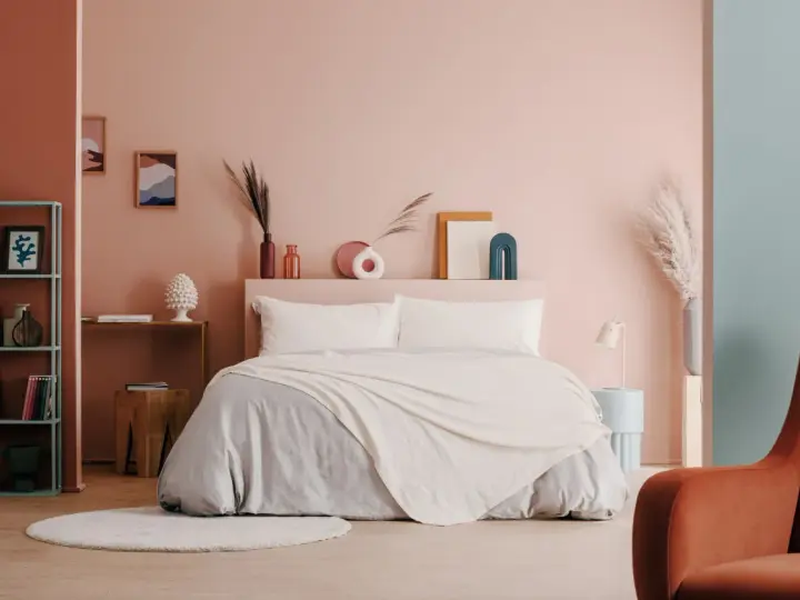 Camera da letto moderna con letto king-size, biancheria grigia e coperta color crema. Idee per come abbellire una camera da letto con decorazioni astratte e piante.