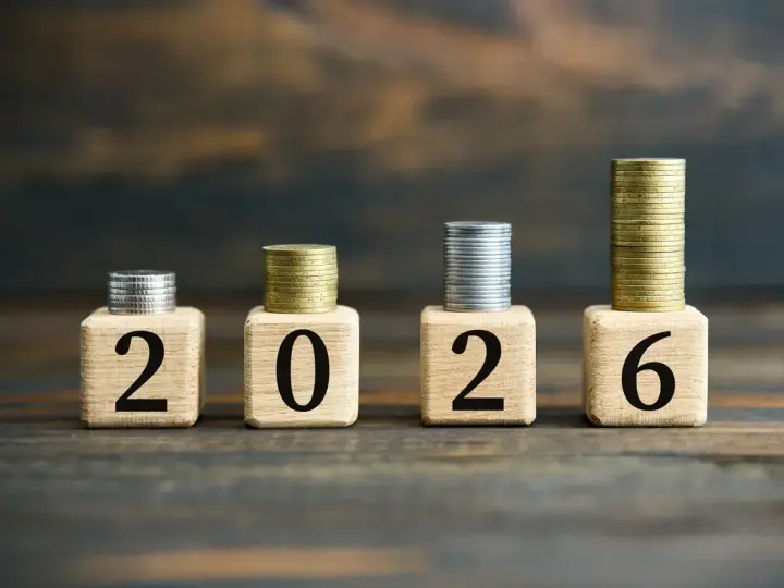 Drewniane klocki z cyframi 2026 i stosy monet.