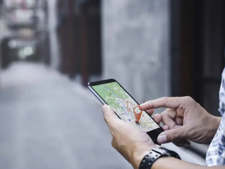 Hombre usando su móvil para localizar una persona por móvil en un mapa.