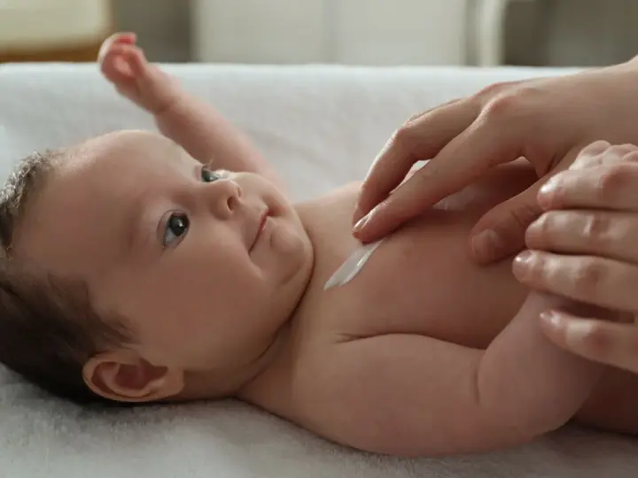 Delikatna pielęgnacja 3 miesięcznego dziecka. Krem na jego klatce piersiowej.