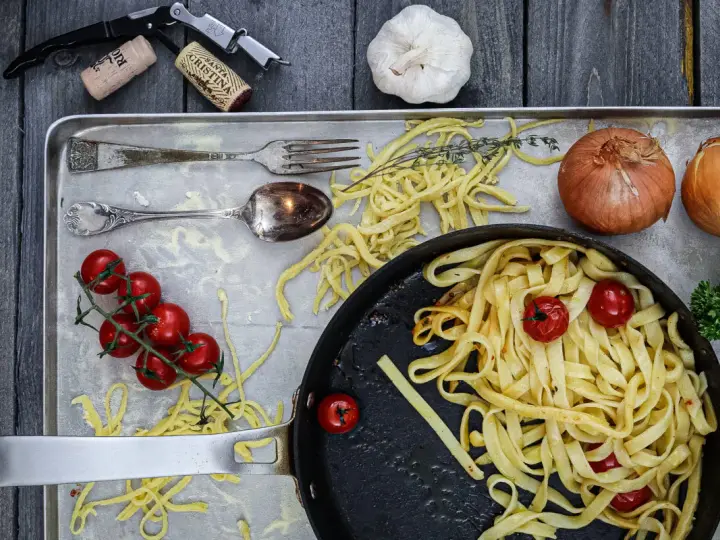 Frische Nudeln aus Hartweizengries, Tomaten, Zwiebeln und Knoblauch auf einem Blech. Ein Festmahl für Genießer!